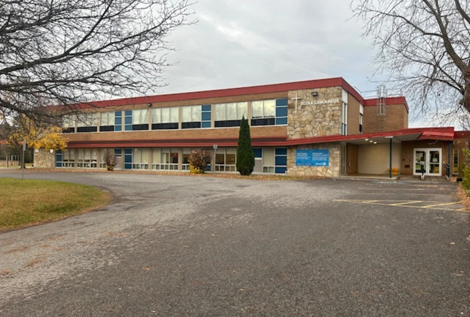 L'École élémentaire catholique Lamoureux vue de son stationnement : un bâtiment de deux étages à toit rouge, avec une croix près de l'entrée.